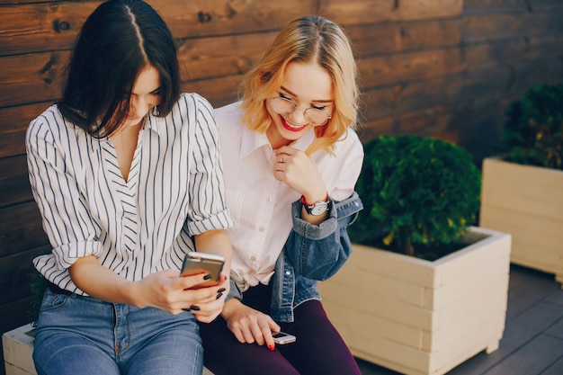 Free photo stylish girls sitting in a city