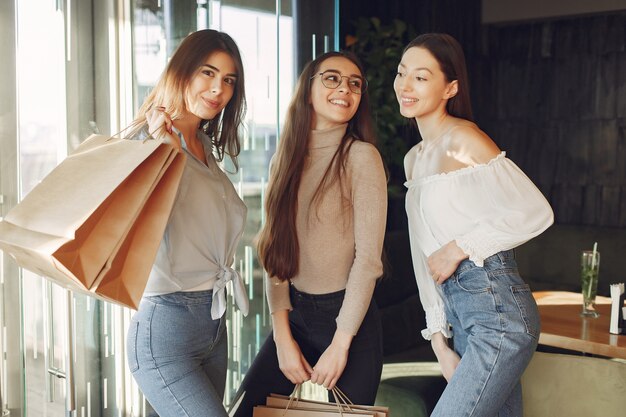 Stylish girls standing in a cafe with shopping bags