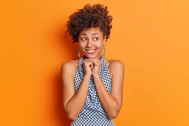 세련된 잘 생긴 아프리카 계 미국인 여성이 턱 미소를 부드럽게 유지하면서 관심을 제쳐두고 보입니다.