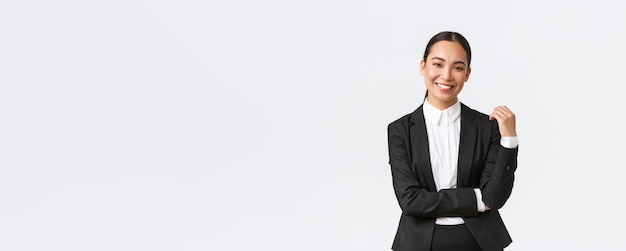 Stylish goodlooking female broker selling houses to clients Asian businesswoman in suit smiling happy and looking confident Successful manager during work white background