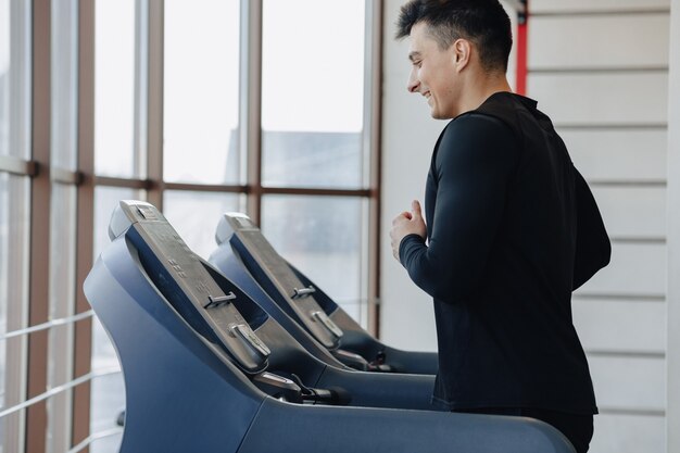 ジムでスタイリッシュな男がトレッドミルでトレーニングしています。健康的な生活様式。