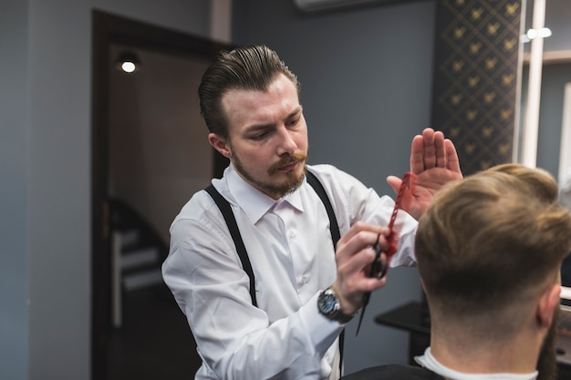 Stylish hairdresser styling hair of man