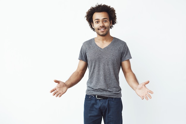 Stylish and handsome african man with arms wide open against white wall inviting to a gig.