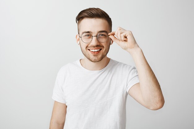 Stylish handsome male in glasses listening music wireless earphones