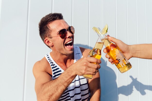 Stylish handsome man in sunglasses enjoying hot summer days, making a toast