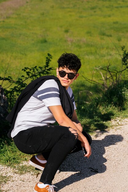 Stylish handsome man wearing eyeglasses and posing on path