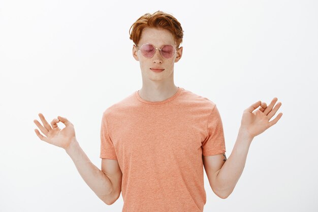 Stylish handsome redhead man in sunglasses, close eyes and meditating