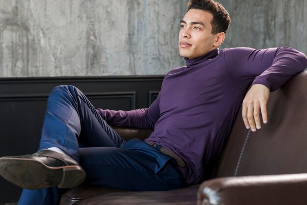 Stylish handsome young man relaxing on sofa looking away