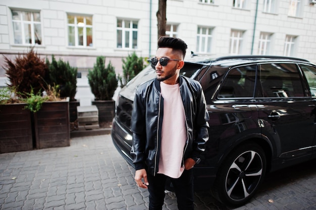 Free photo stylish indian beard man at black leather jacket and sunglasses against business suv car india model posed outdoor at streets of city