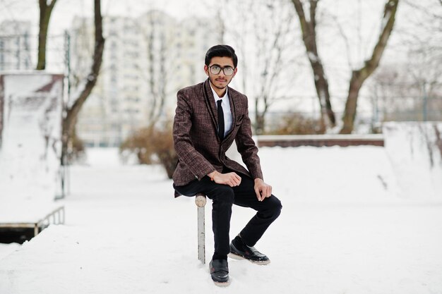 冬の日の屋外でポーズをとったスーツとメガネのスタイリッシュなインドの学生男性
