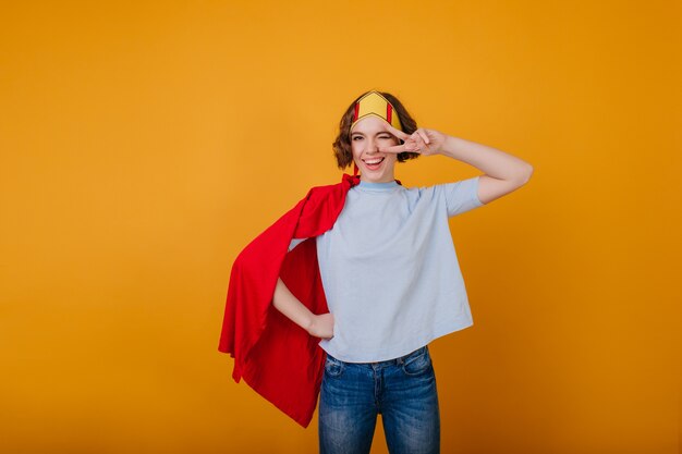 Stylish lady in funny paper crown posing with peace sign