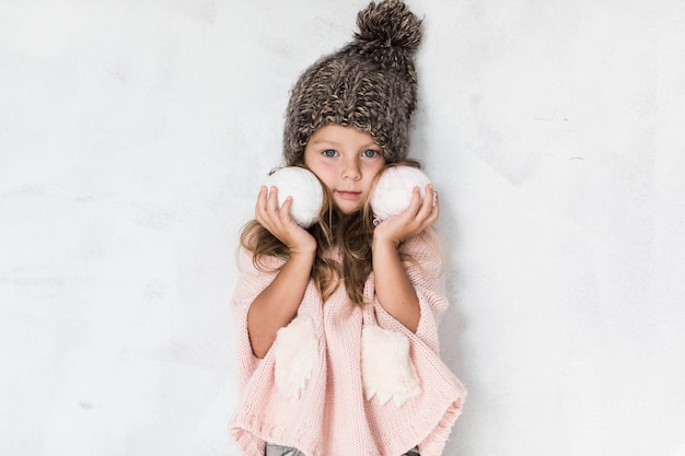 Stylish little girl holding snowballs