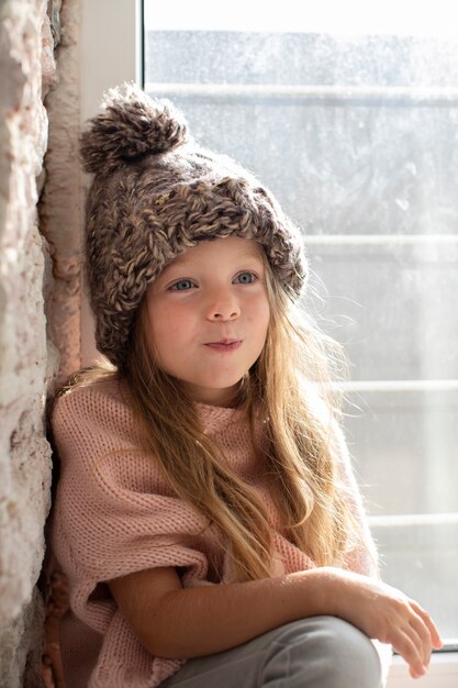 Стильная маленькая девочка позирует в зимней шапке