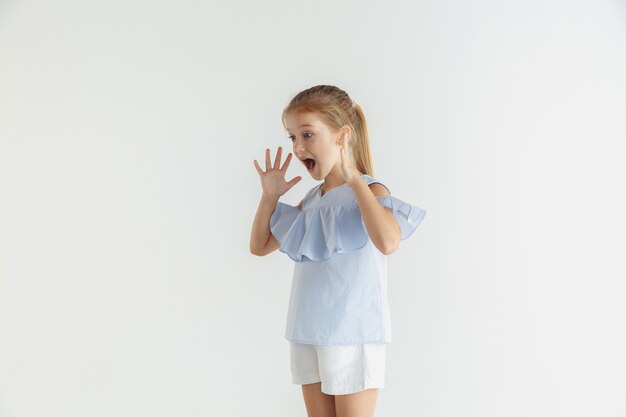 Stylish little smiling girl posing in casual clothes isolated. Caucasian blonde female model. Human emotions, facial expression, childhood. Shocked, astonished.