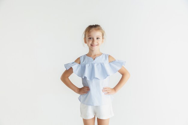 화이트 스튜디오에 고립 된 캐주얼 옷을 입고 포즈 세련 된 작은 웃는 소녀