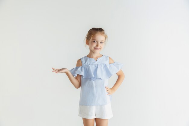 화이트 스튜디오에 고립 된 캐주얼 옷을 입고 포즈 세련 된 작은 웃는 소녀