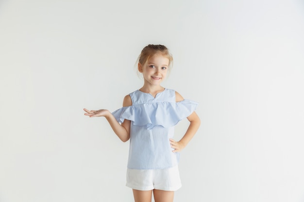 Stylish little smiling girl posing in casual clothes isolated on white studio