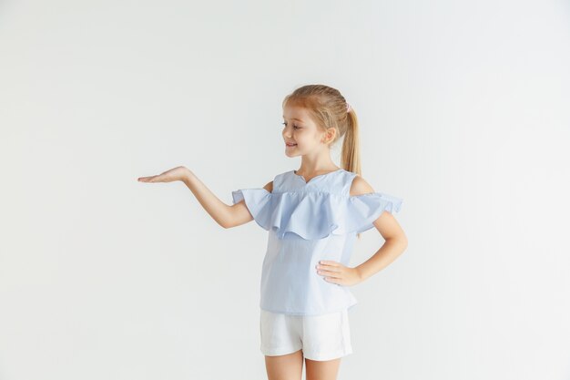 Stylish little smiling girl posing in casual clothes isolated on white studio