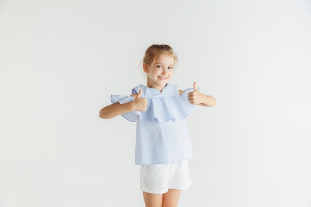 Elegante bambina sorridente in posa in abiti casual isolati su bianco studio