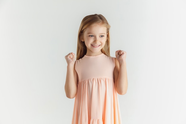 Elegante bambina sorridente in posa in abito isolato su uno spazio bianco. modello femminile biondo caucasico. emozioni umane, espressione facciale, infanzia