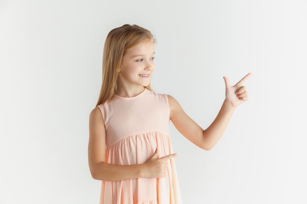 Stylish little smiling girl posing in dress isolated on white studio