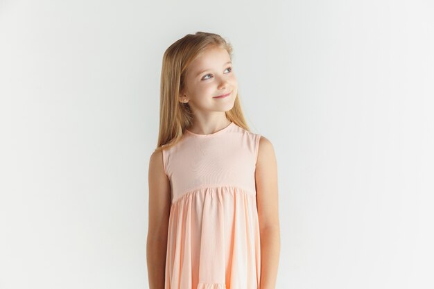 화이트 스튜디오에 고립 된 드레스를 입고 포즈를 취하는 세련 된 작은 웃는 소녀