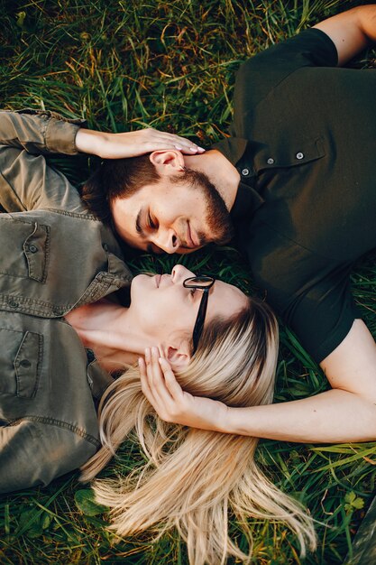 Stylish loving couple lying in a park. A beautiful girl is having a good time with her boyfriend