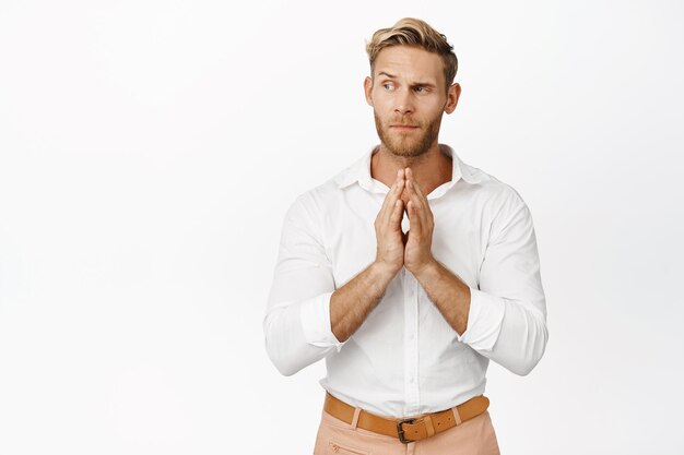 Stylish macho man planning scheming and thinking of smth interesting steeple fingers like evil genius standing thoughtful over white background