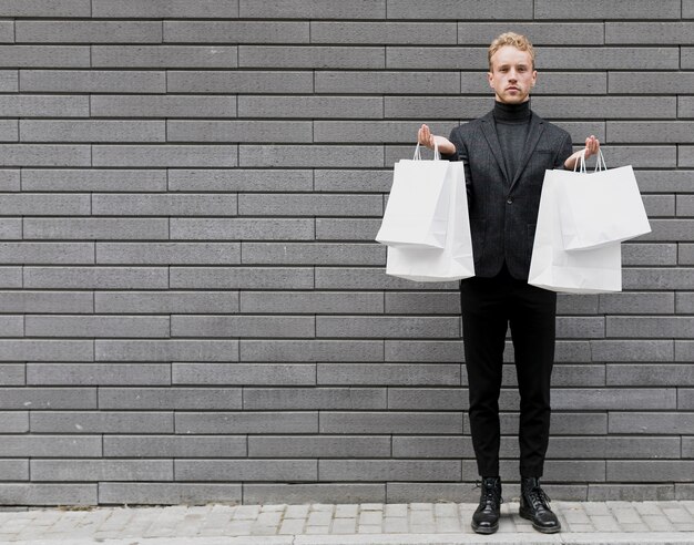 Stylish man in black with white shopping bags