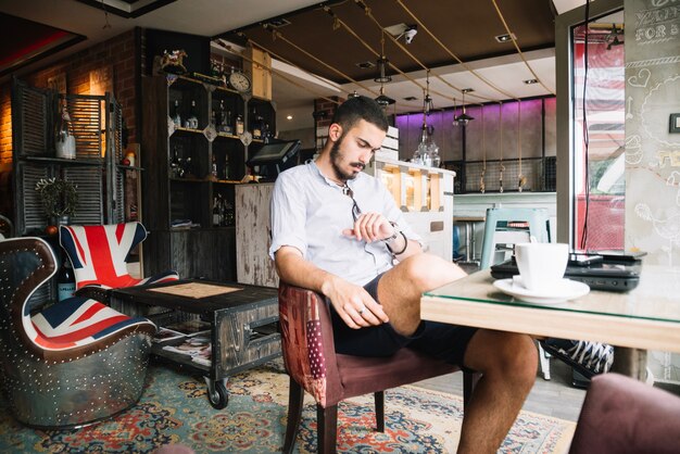 Foto gratuita uomo alla moda in caffè controllando il tempo