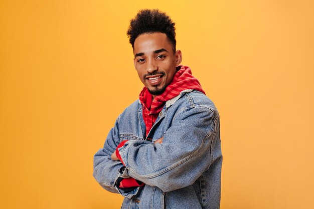 Stylish man in denim outfit posing on orange wall