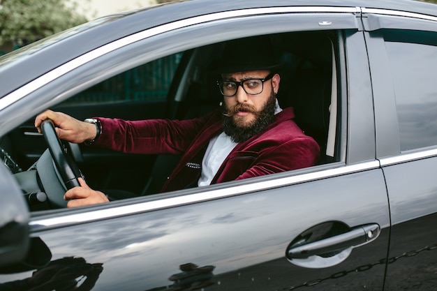 高級車を運転するスタイリッシュな男