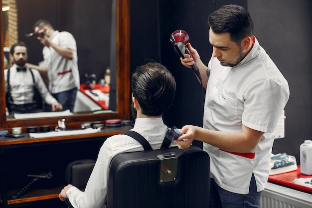 Foto gratuita elegante uomo seduto in un negozio di barbiere