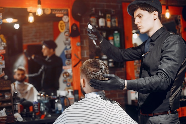 Foto gratuita elegante uomo seduto in un negozio di barbiere