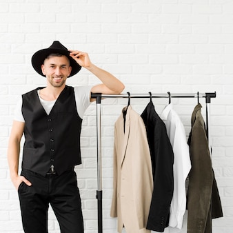 Стильный мужчина в шляпе и стоит рядом с гардеробом