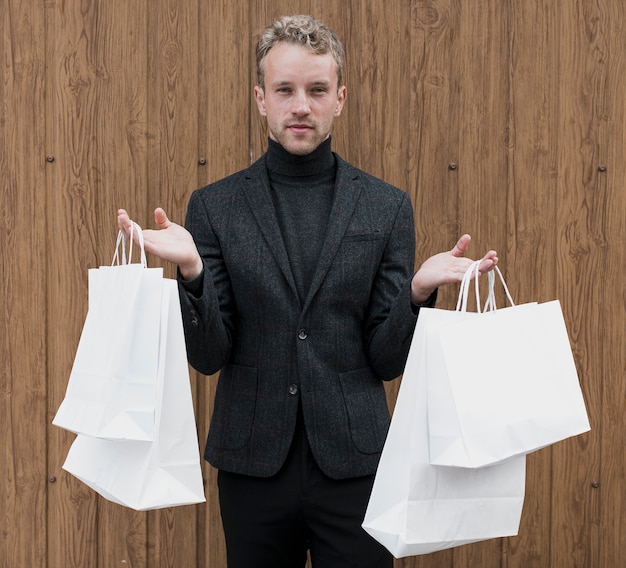 Free photo stylish man with shopping bags in both hands