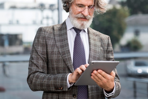 Стильный зрелый мужчина просматривает планшет