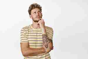 Free photo stylish modern guy thinking looking up thoughtful choosing or making decision standing over white background