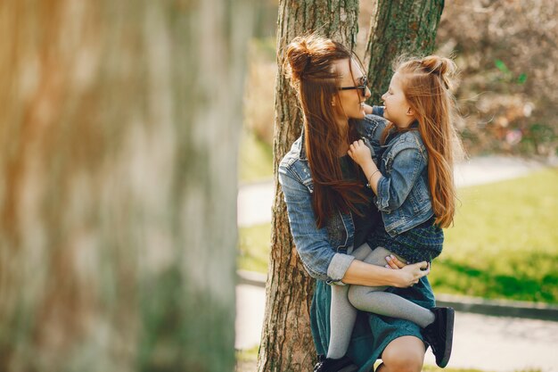 stylish mother with long hair and a jeans jacket playing with her little cute daughter