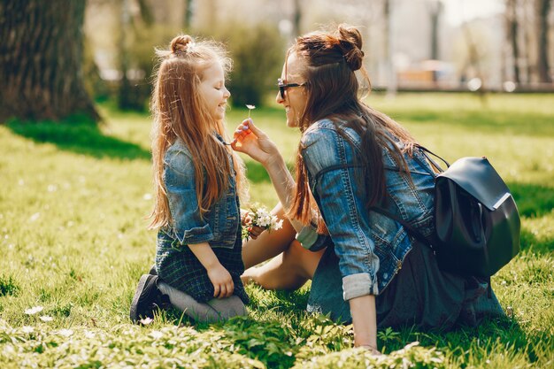 stylish mother with long hair and a jeans jacket playing with her little cute daughter