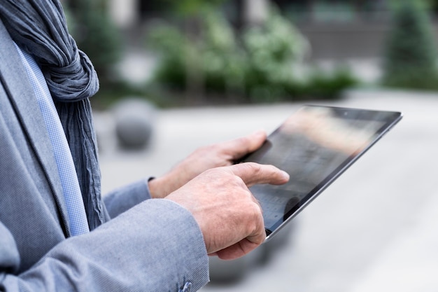 Stylish older man in the city using tablet