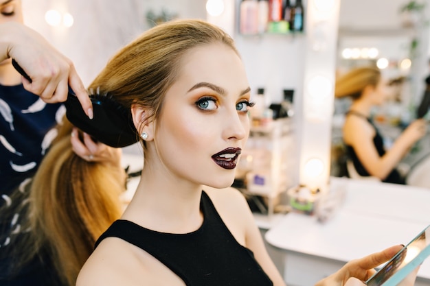 Stylish portrait of attractive young woman in beauty salon preparing to party