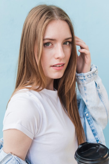 Stylish pretty woman looking at camera holding disposable coffee cup