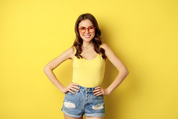 Stylish pretty woman posing in sunglasses and summer clothes looking happy and carefree concept of v...