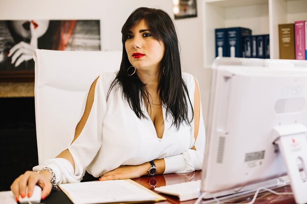 Stylish secretary posing at table with computer