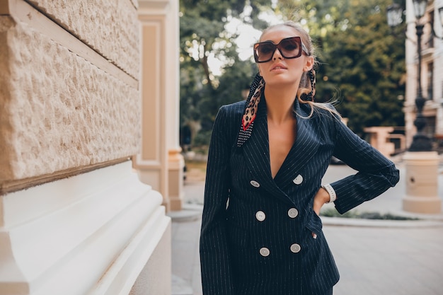 Free photo stylish sexy woman dressed in elegant tuxedo suit walking in city on summer spring day