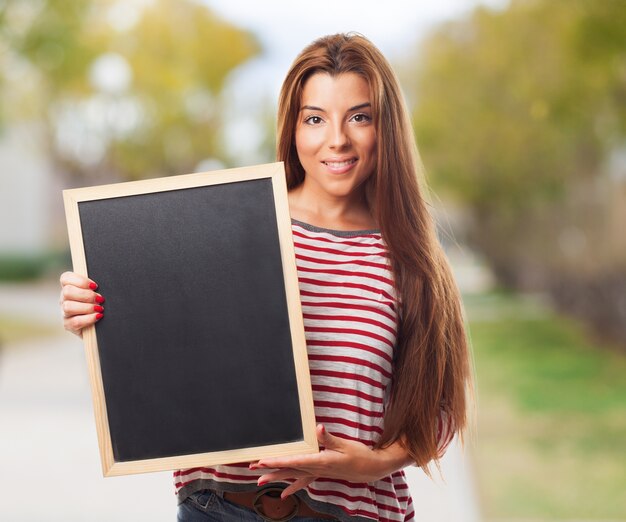Stylish student girl holding small blackboard