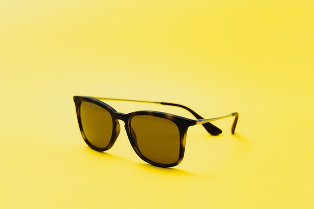 黄色の背景にスタイリッシュなサングラス高品質の写真サングラス。