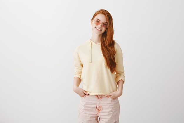 Stylish teenage redhead in sunglasses smiling