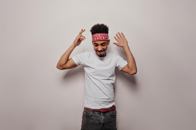 Stylish teenager guy dancing on white background Attractive happy brunette man in white tee and black pants posing on isolated backdrop